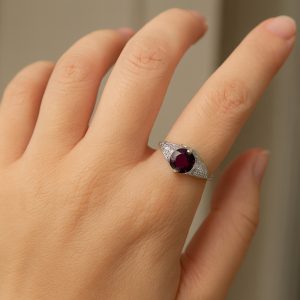 Platinum vintage-inspired ring set with a 7.3 mm 1.80 carat magenta rhodolite and 8 diamonds totaling .24 carat.